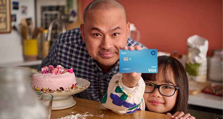A daughter standing next to her father and showing off her Chase First Banking debit card